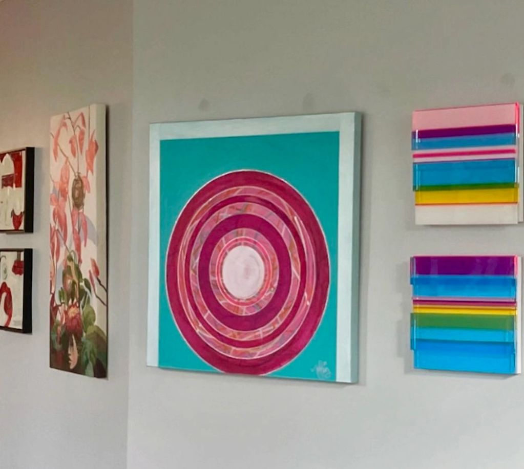 Colorful abstract paintings with circular and striped designs on a wall.