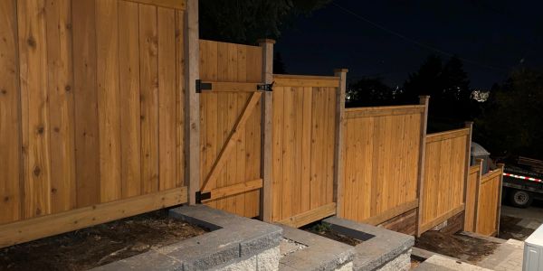 Wooden fence and gate on a sloped yard at night.
