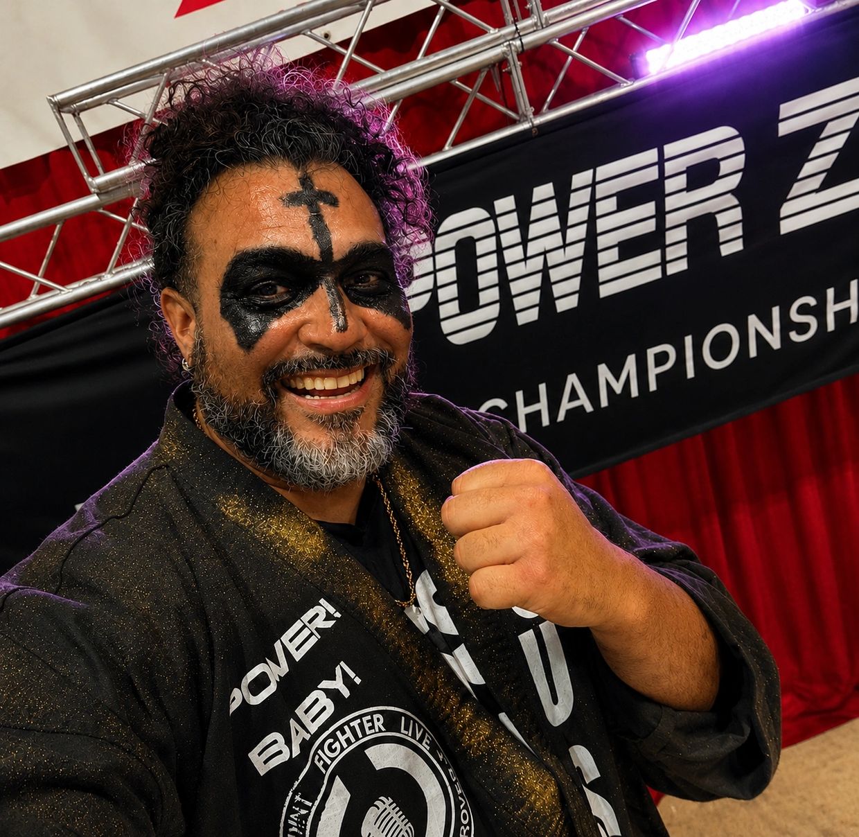 Smiling man with face paint and clenched fist.