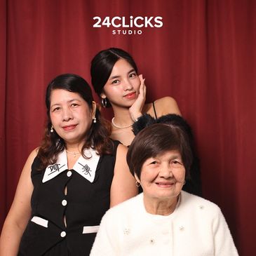 Three generations of women posing in front of a red curtain.