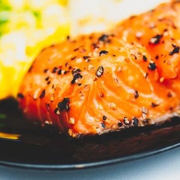 Close-up of seasoned cooked salmon on a black plate.
