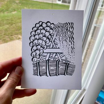 A hand holds a black and white abstract drawing near a window.