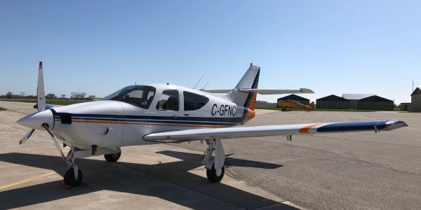 Small single-engine propeller airplane parked on an airstrip.