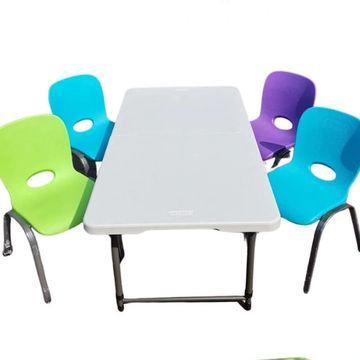 A white rectangular table surrounded by colorful chairs with blue, green, and purple seats.