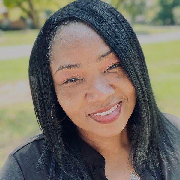 Smiling woman with straight black hair outdoors in natural light.