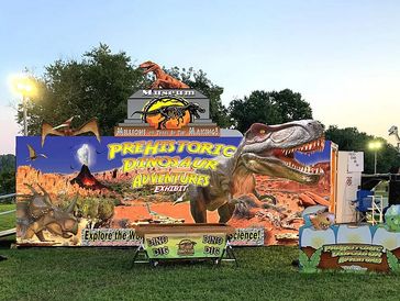 Colorful sign for Prehistoric Dinosaur Adventures exhibit at a museum.