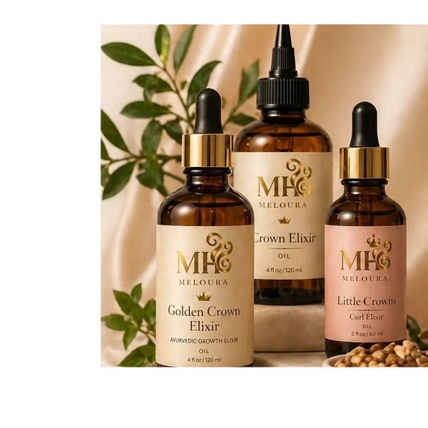 3 hair oils in amber bottles on a satin background with green leaves faintly behind them.