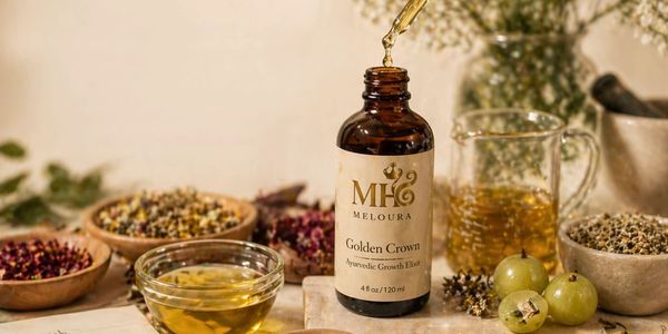 An amber glass bottle dripping oil, centered around botanical ingredients on a neutral background.