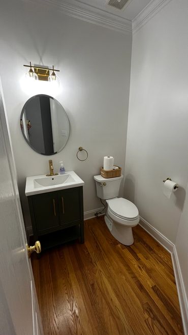 Simple bathroom with wooden floor, white walls, and gold fixtures.
