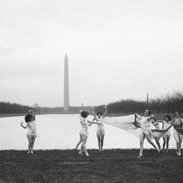 Women dancing near the Reflecting Pool with Washington Monument in background.