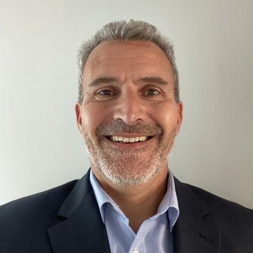 Smiling middle-aged man in a suit and light blue shirt.