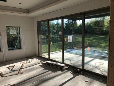 Room under construction with large glass sliding doors and scattered wood pieces.