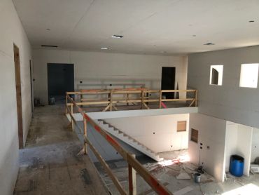 Interior view of a building under construction with stairs and wooden railings.