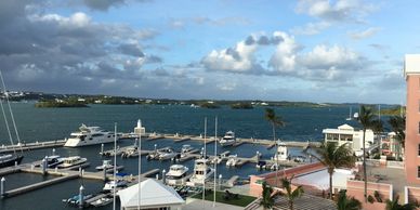 Scenic marina with boats docked under a partly cloudy sky.