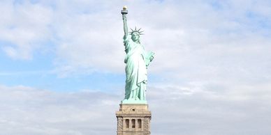 The Statue of Liberty stands tall against a partly cloudy sky.