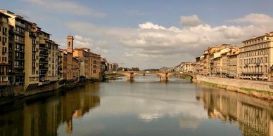 Historic bridges and buildings lining the calm river in a European city.