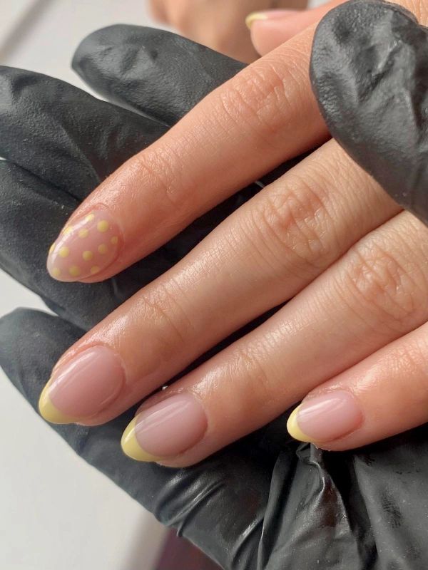 Yellow French manicure with polka dot accent nail.