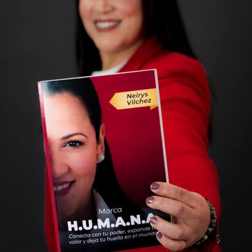Mujer mostrando un libro llamado H.U.M.A.N.A.S.