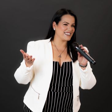 Mujer sonriente cantando con micrófono.