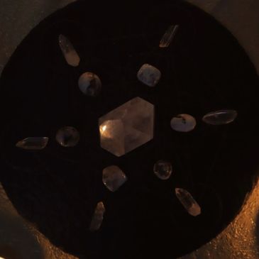 Crystals arranged in a geometric pattern on a dark surface.
