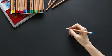 A person holding a colored pencil about to draw.