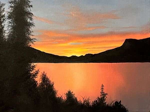 Sunset reflecting over a calm lake with silhouetted trees and hills.