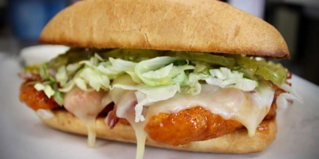 Close-up of a crispy chicken sandwich with lettuce and melted cheese.
