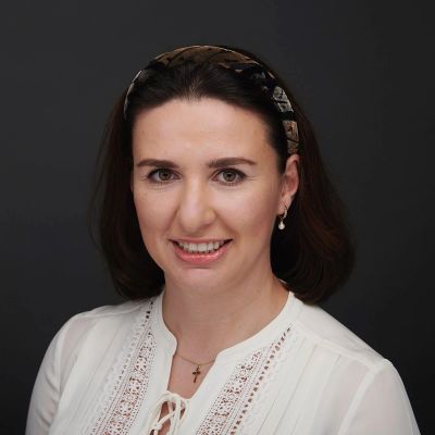 Professional woman smiling against a black backdrop.