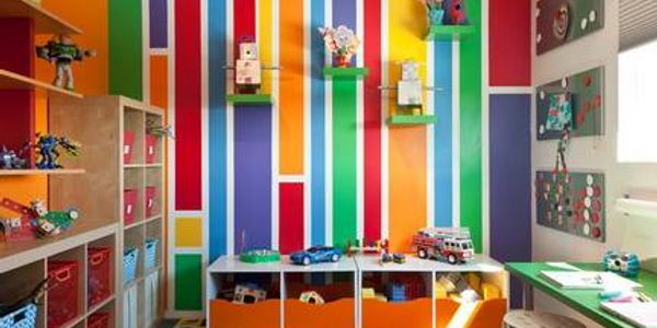 Bright and colorful kids' room with striped walls and organized toys.