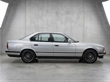 Silver vintage sedan parked in a minimalist industrial space.