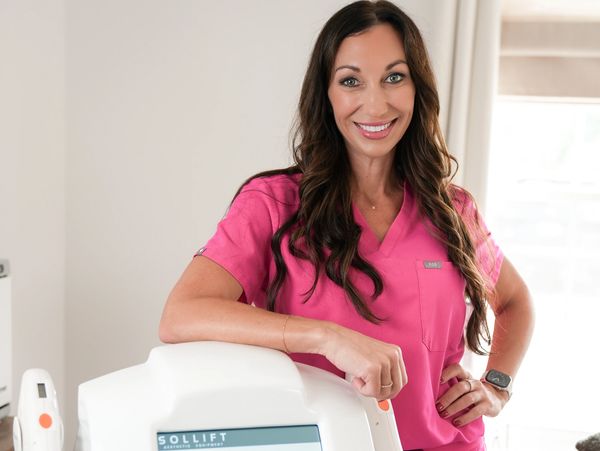 Smiling woman in pink scrubs indoors.