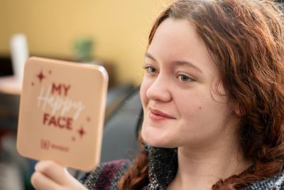 Young woman looking at a handheld mirror.