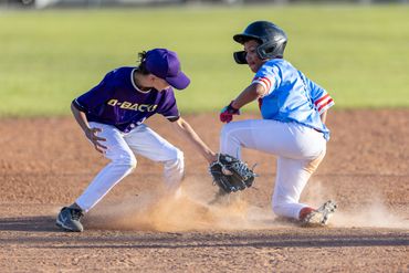 Two young baseball players in action during a game, with one sliding and the other tagging.