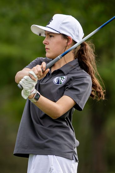 Young female golfer focused on her swing during a game.