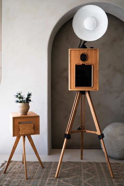 Vintage wooden camera on tripod with matching side table and plant.