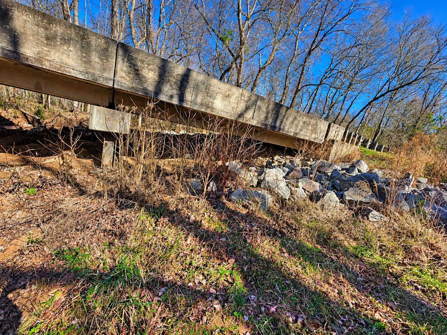 Concrete guardrail with rocky and grassy area under it.