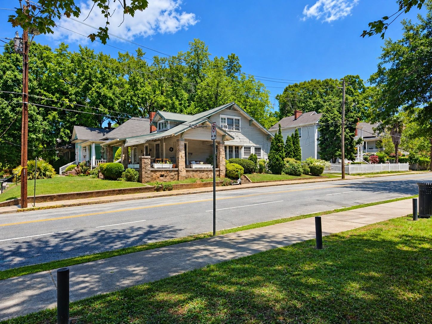 Sunny neighborhood street with cozy homes and lush greenery.