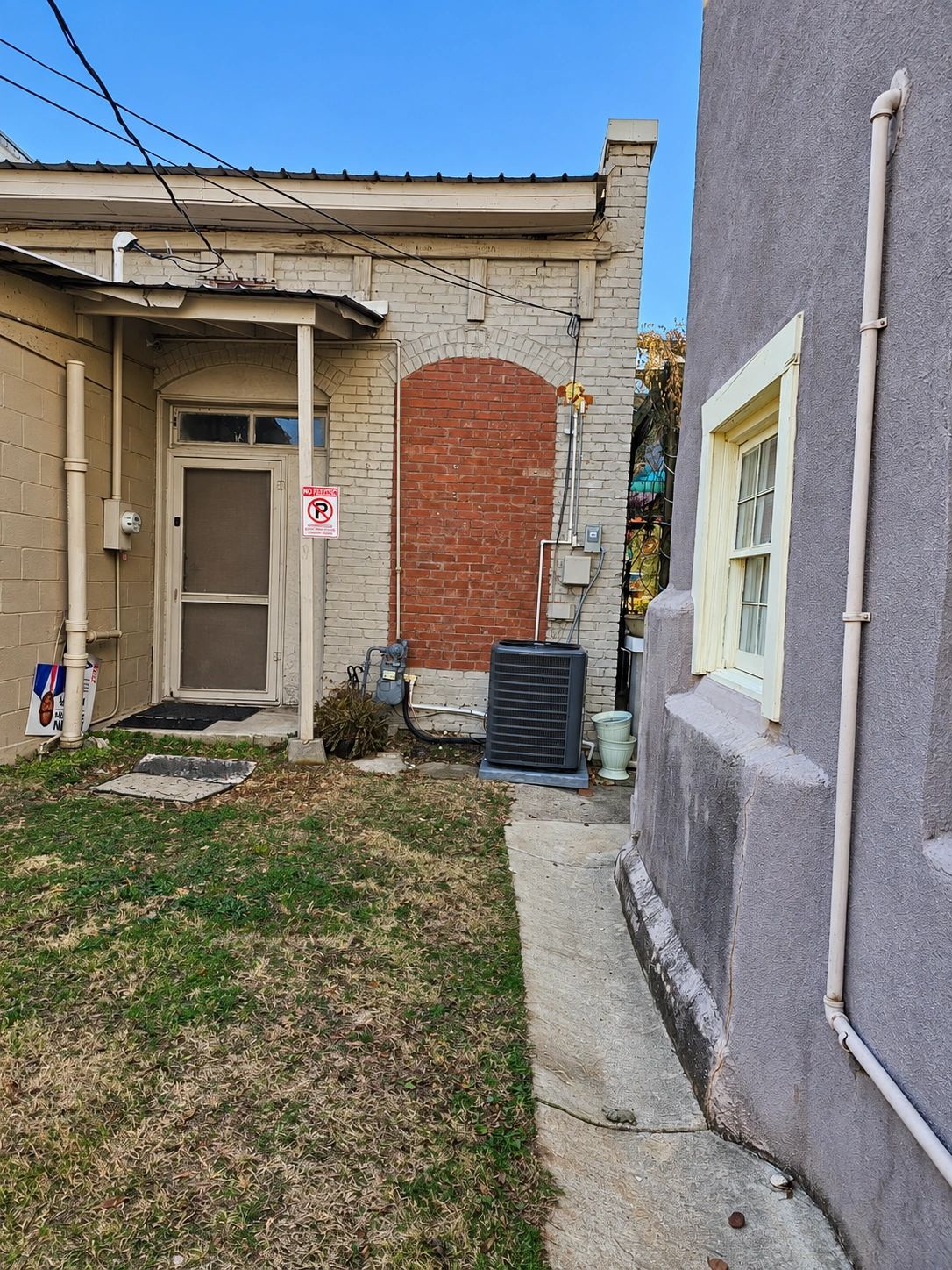 Backyard of two buildings with an air conditioning unit.