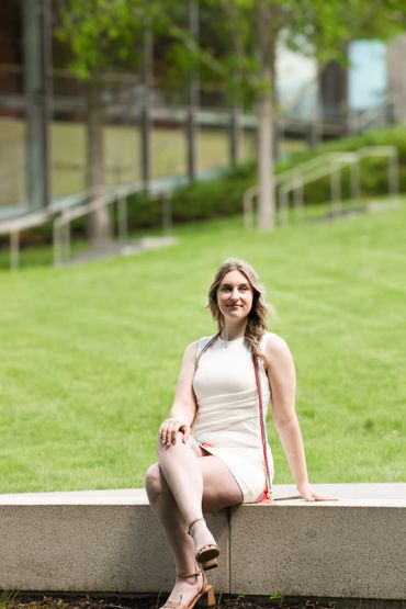 Young woman in white dress sitting on a stone bench outdoors.