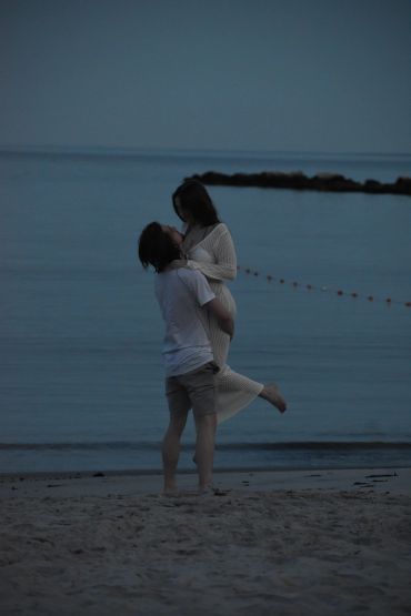 Couple embracing by the beach at dusk.