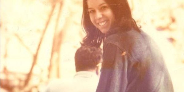 Woman smiling over shoulder outdoors.