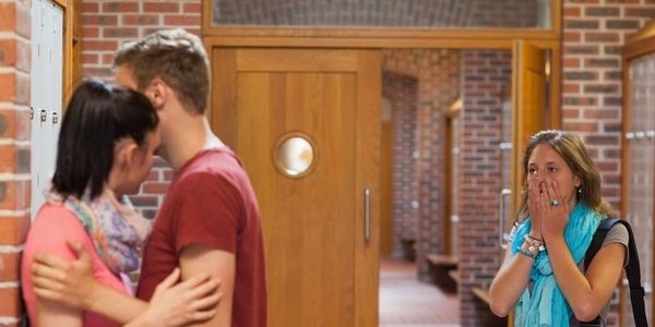 A distressed girl watches a couple embrace at school.
