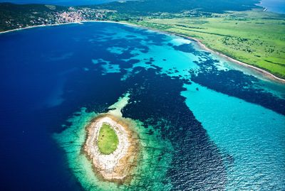 Aerial view of a small island near the coast with vibrant blue waters.