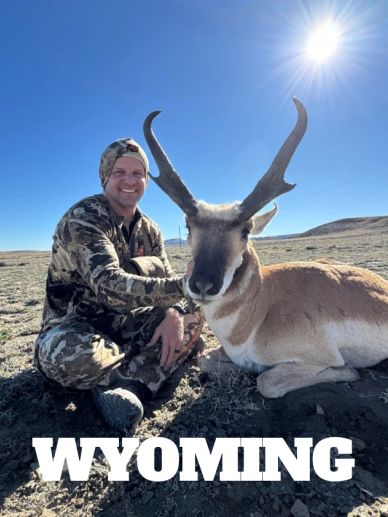 Hunter posing with a pronghorn antelope in Wyoming under a bright sun.