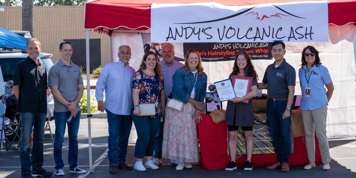Group of people posing in front of Andy's Volcanic Ash tent at an outdoor event.