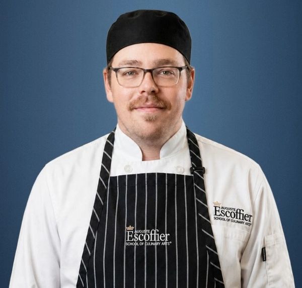 Chef in Escoffier culinary school uniform with glasses and a black cap.