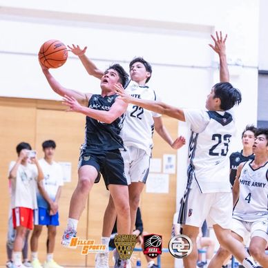 Young basketball player in black attempts a layup against defenders in white jerseys.
