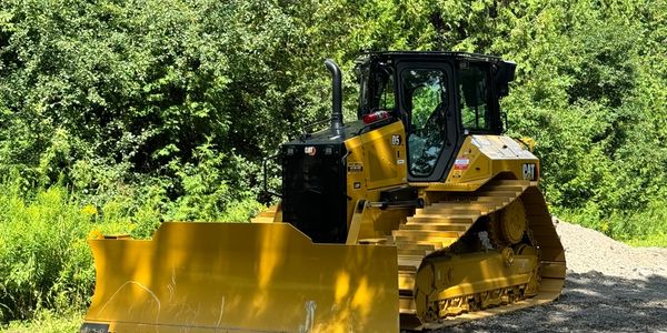 Yellow Caterpillar bulldozer in a forest clearing on gravel.