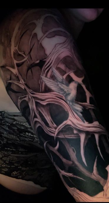 Intricate tattoo sleeve with a hummingbird and abstract organic patterns.