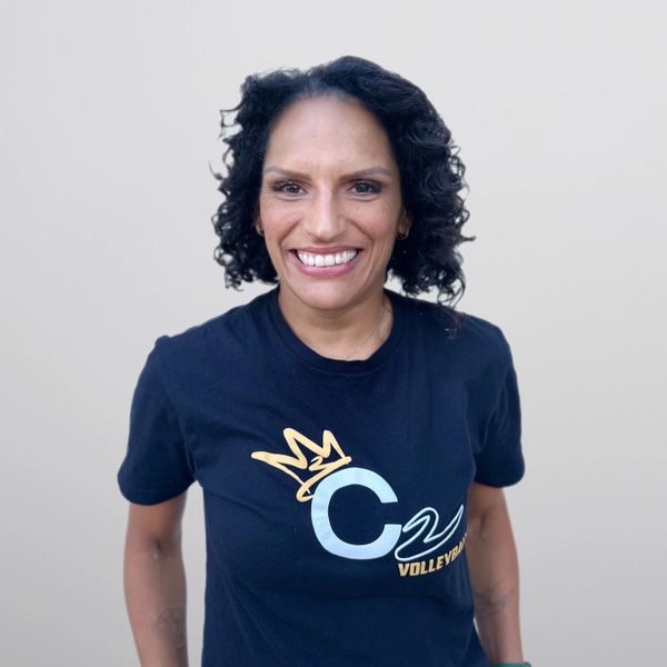 Woman smiling, wearing a black t-shirt with a volleyball logo.